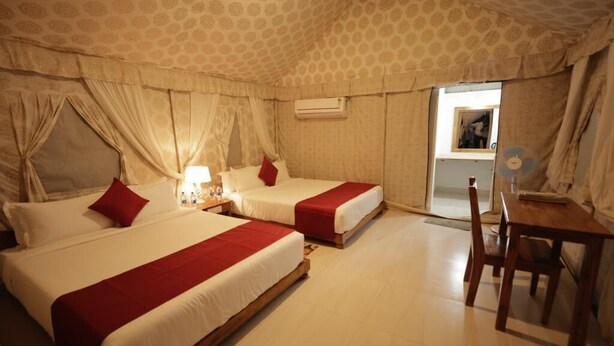 A hotel room with two beds, a table, and a chair. - Ken Resort (Panna)