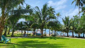 Een weelderig, groen gazon met palmbomen en uitzicht op de zee.
