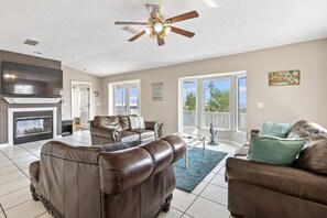 A spacious living room with a fireplace, leather sofas, a television, and a ceiling fan. - Sea Forever Pet Friendly Sleeps 14 Large Family Home Close To The Beach With Ocean Views (Flagler Beach)