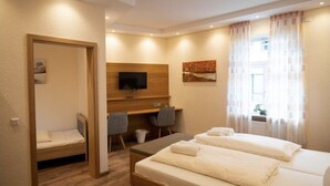 A hotel room with two beds, a desk, a TV, and a window with curtains. - zur Krone (Leimen)