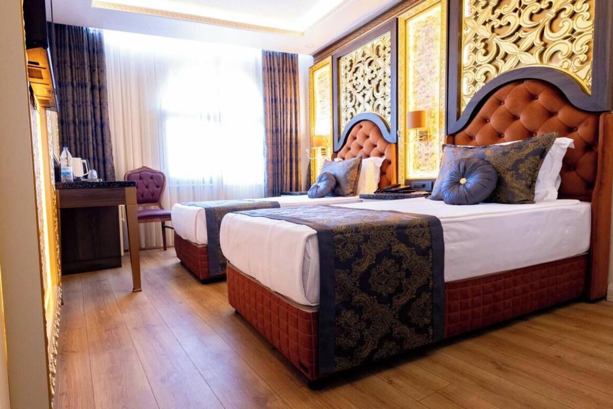 Habitació d'hotel amb dos llits, un escriptori i una cadira.