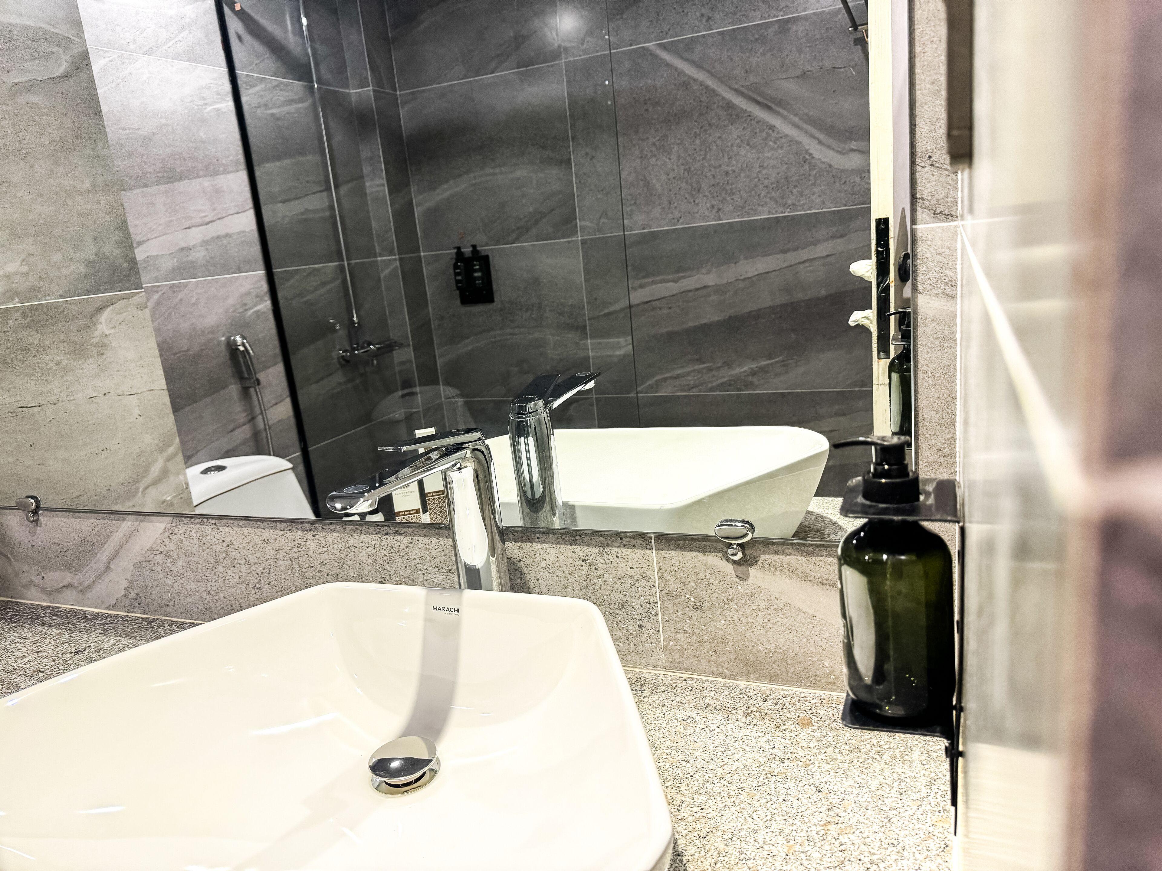 Un baño con lavamanos blanco, un espejo, ducha y retrete.