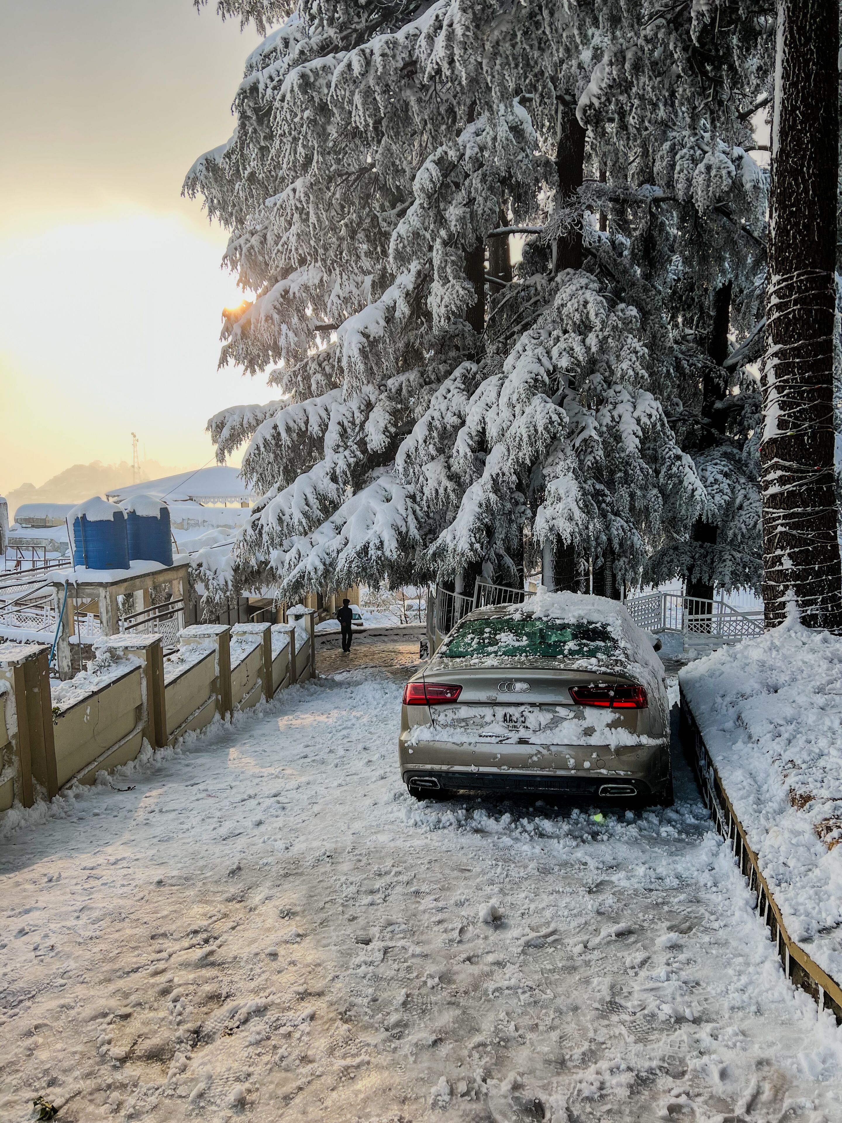 Eine verschneite Straße mit einem geparkten Auto und einer Person, die gerade geht.