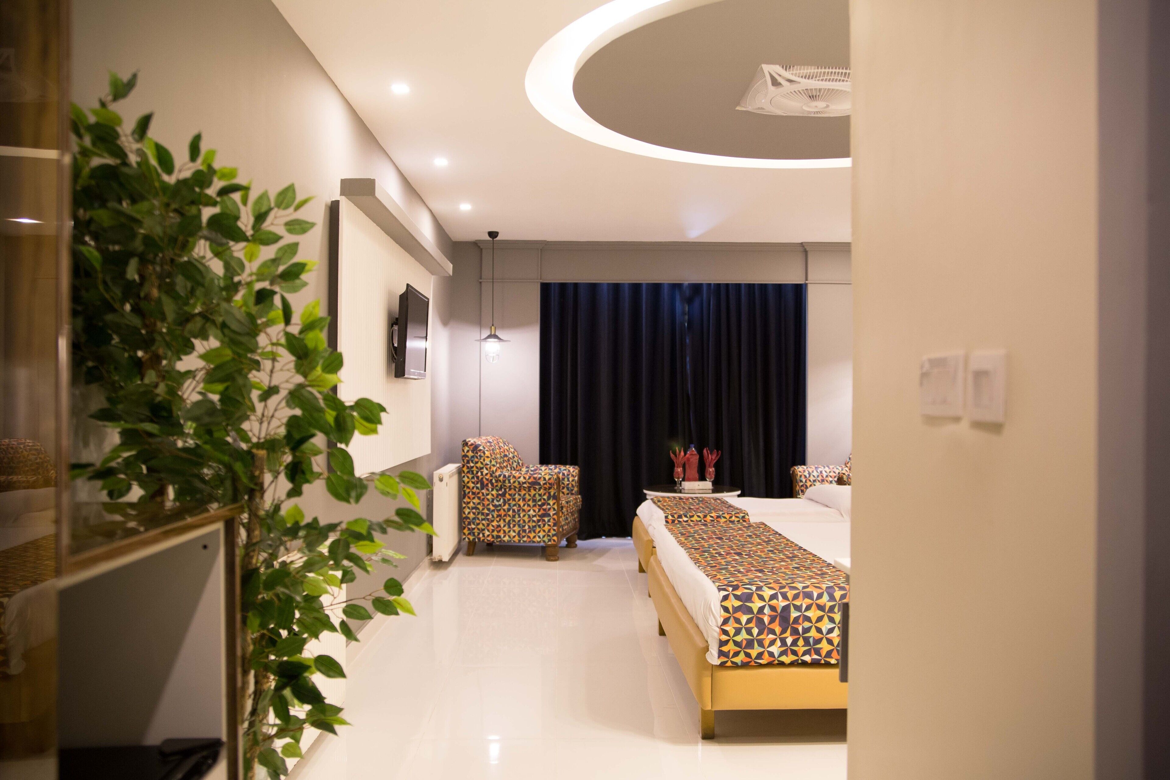 Une chambre d’hôtel moderne dotée d’un grand lit, d’un coin salon et d’une plante.