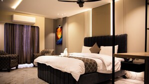 A modern hotel room with a large bed, a ceiling fan, a flat-screen TV, and a marble floor. - Hotel Metropole (Murree)
