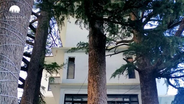 A building with a symmetrical facade, large windows, and a central entrance flanked by columns. - Hotel Metropole (Murree)