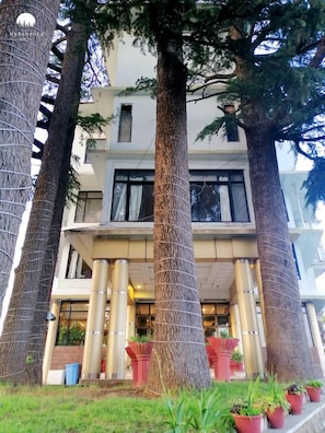 A building with a symmetrical facade, large windows, and a central entrance flanked by columns. - Hotel Metropole (Murree)