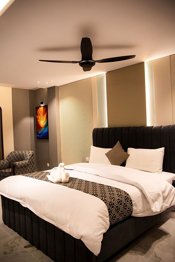 Un dormitorio moderno con una cama grande, un ventilador de techo y un televisor montado en la pared.