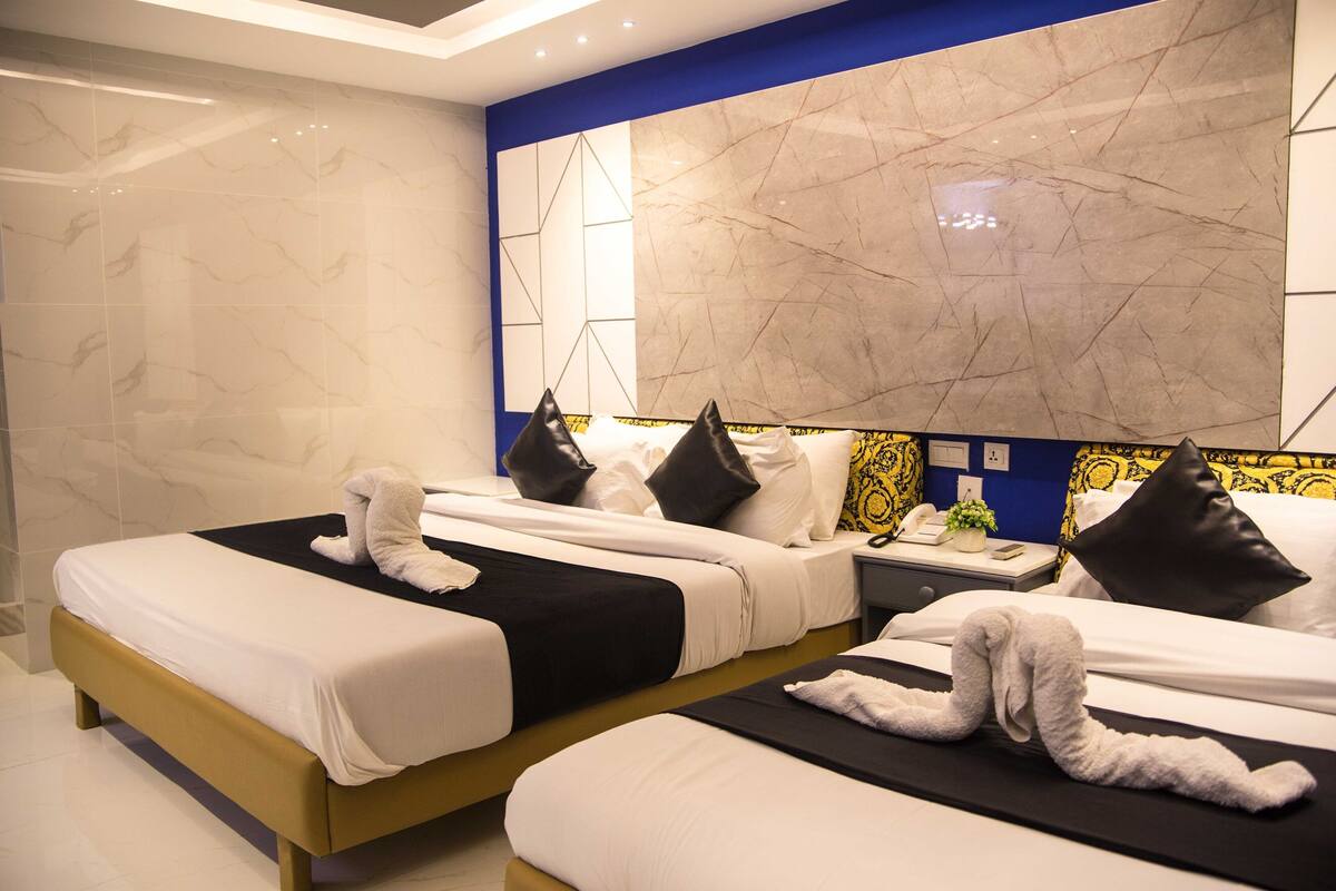 A hotel room with two beds, each with neatly folded towels and black and white bedding.