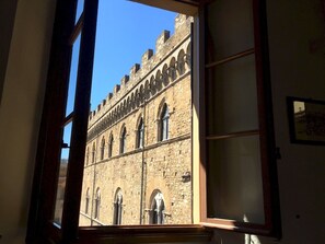 A view through a window of a historic building with arched windows and stone walls.