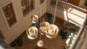 Un patio amplio con sillones colgantes, una escalera y un balcón con puertas de madera.