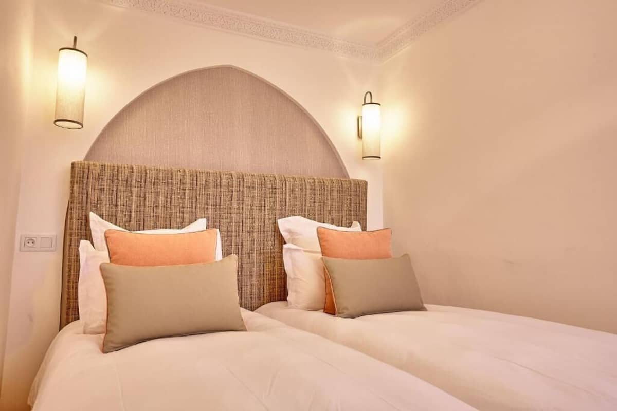 A double bed with a headboard, two wall-mounted lights, and a plain wall.