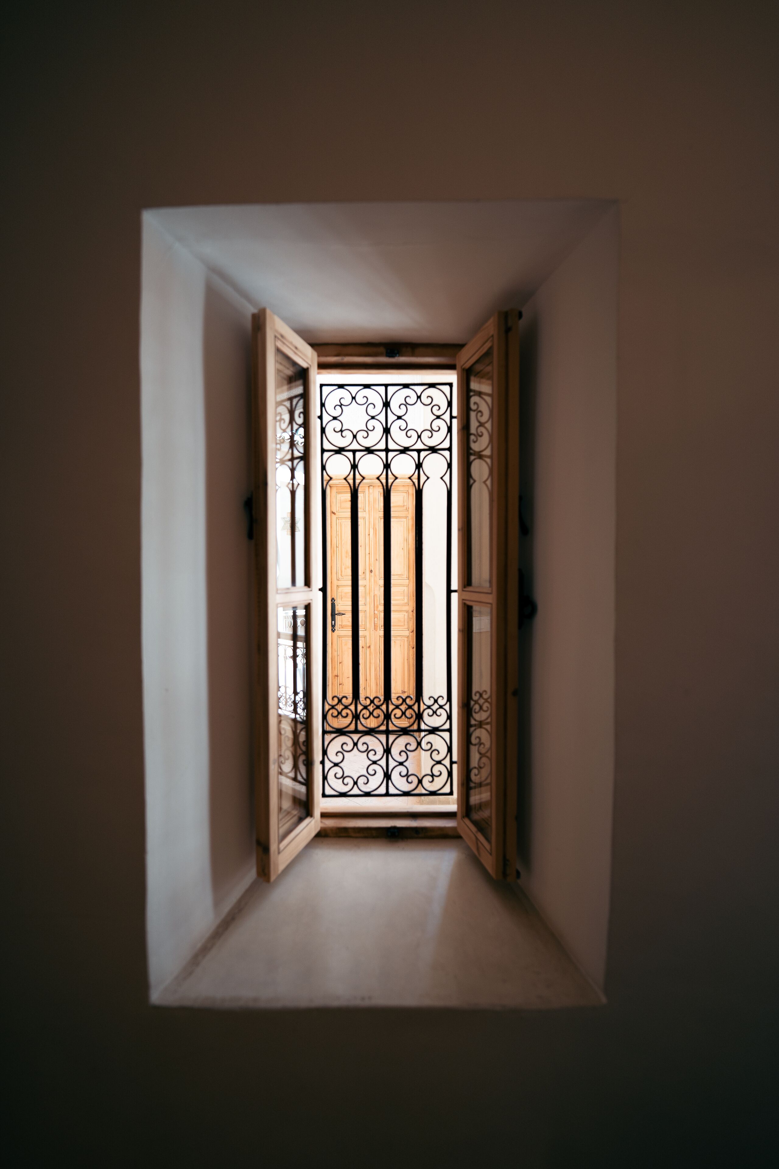 Un pasillo estrecho y tenuemente iluminado con una puerta de madera y ornamentación metálica detallada.