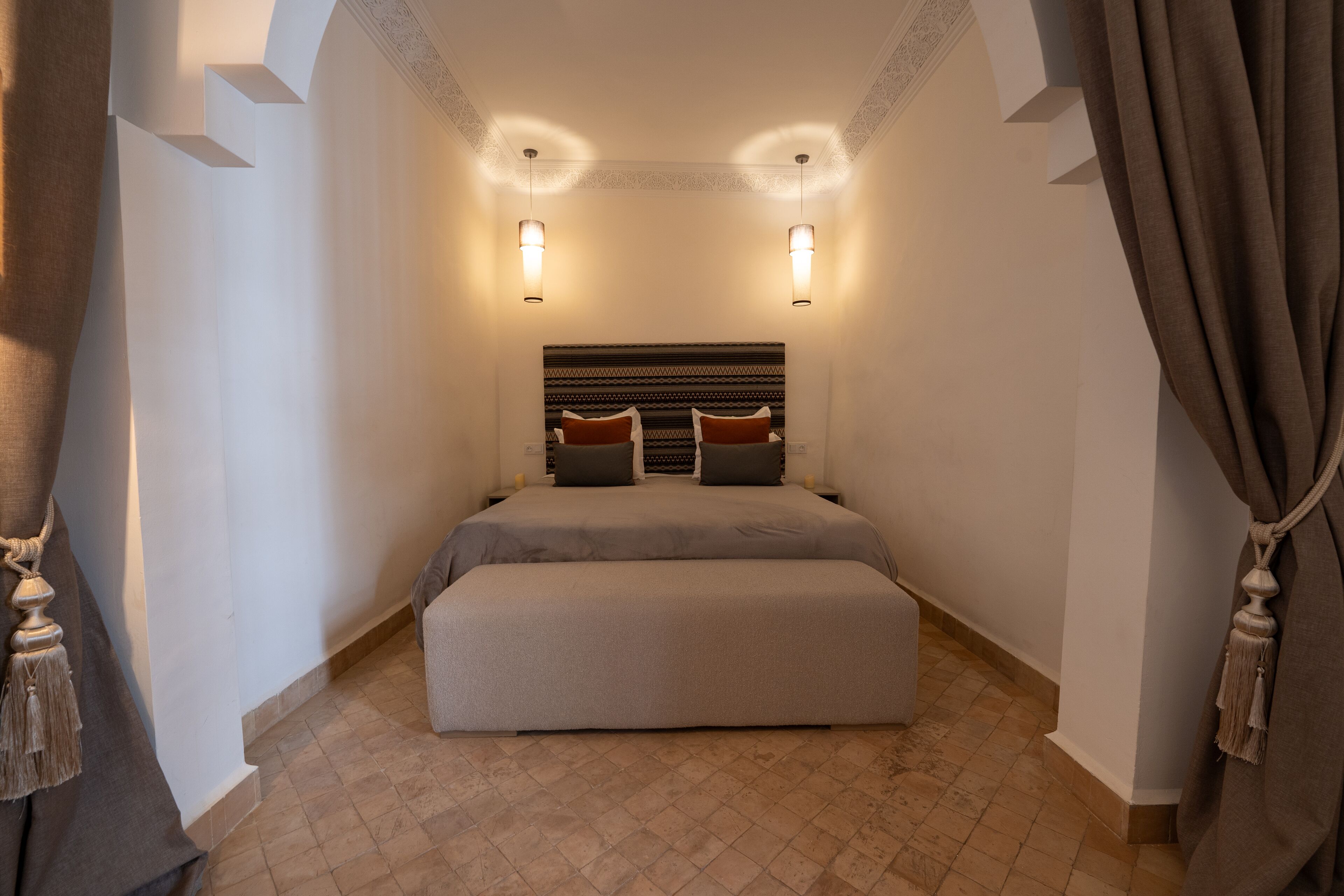 Une chambre à coucher avec un grand lit, deux lampes de chevet et une tête de lit ornée d’un motif décoratif.