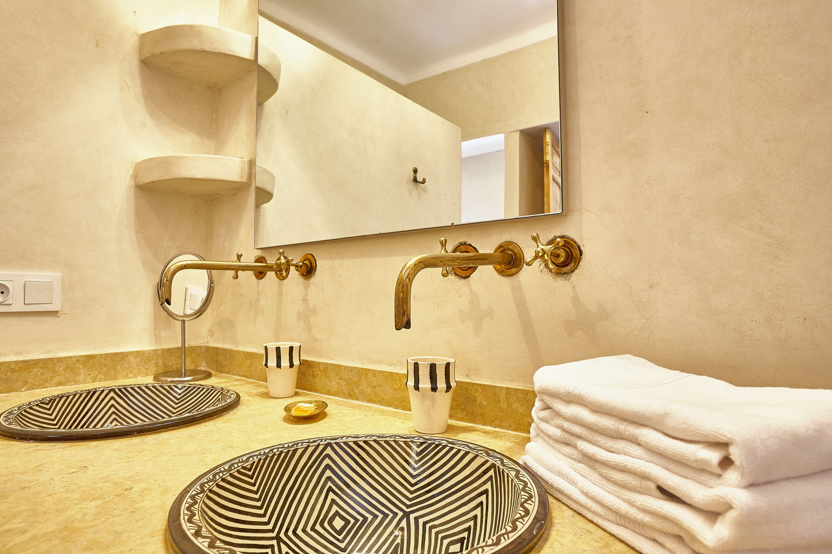 A bathroom with two sinks, a mirror, and a towel stack.