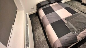 A bedroom with a bed, a heater, a mirror, and a wall-mounted picture. - Delightful holiday home away from home, wetroom, UFH, garden/parking, local park (London)