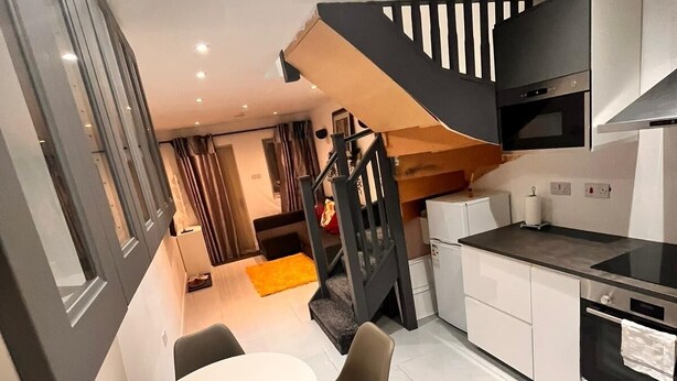 A modern kitchen with a dining area, featuring a staircase, built-in appliances, and a large window. - Delightful holiday home away from home, wetroom, UFH, garden/parking, local park (London)