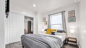Une chambre à coucher avec un lit, une armoire, une fenêtre avec des rideaux et une table de chevet.