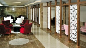 Una hall con pavimento in marmo, sedie rosse e bianche e un tavolino da caffè in vetro.