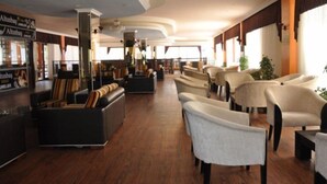 Un'ampia hall con file di posti a sedere, un'area bar e ampie finestre che lasciano entrare la luce naturale.
