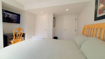 Een hotelkamer met een bed, een aan de muur bevestigde televisie, een houten stoel en een deur.