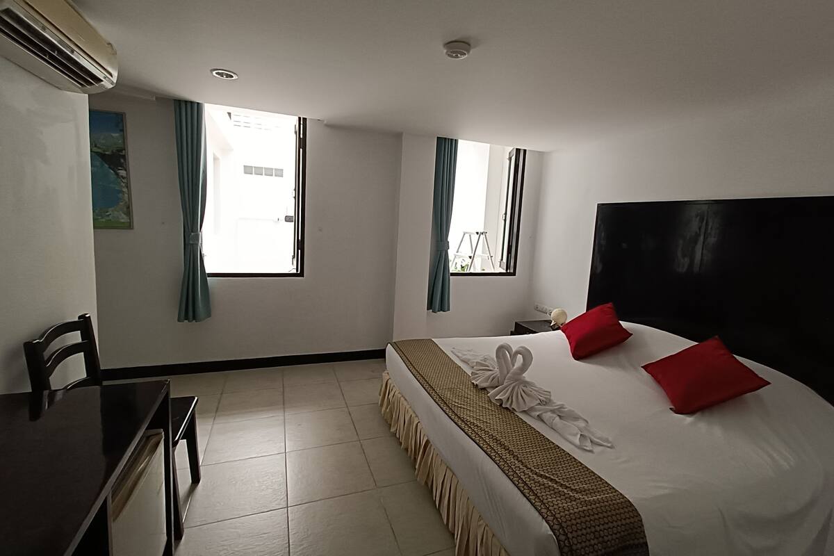 Une chambre d’hôtel avec un lit, un bureau et deux fenêtres.