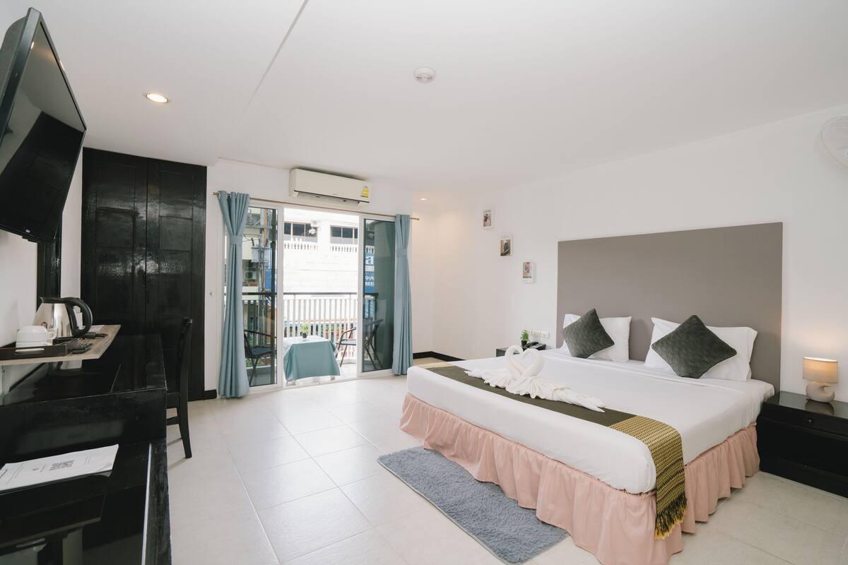 Une chambre d’hôtel avec un lit, un bureau équipé d’un ordinateur, un piano et un balcon offrant une vue.