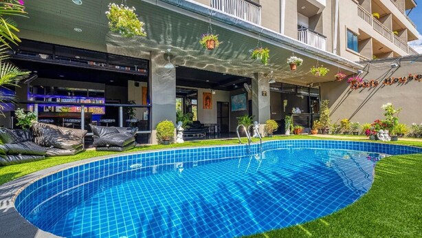 A hotel with a swimming pool, outdoor seating, and a bar area.