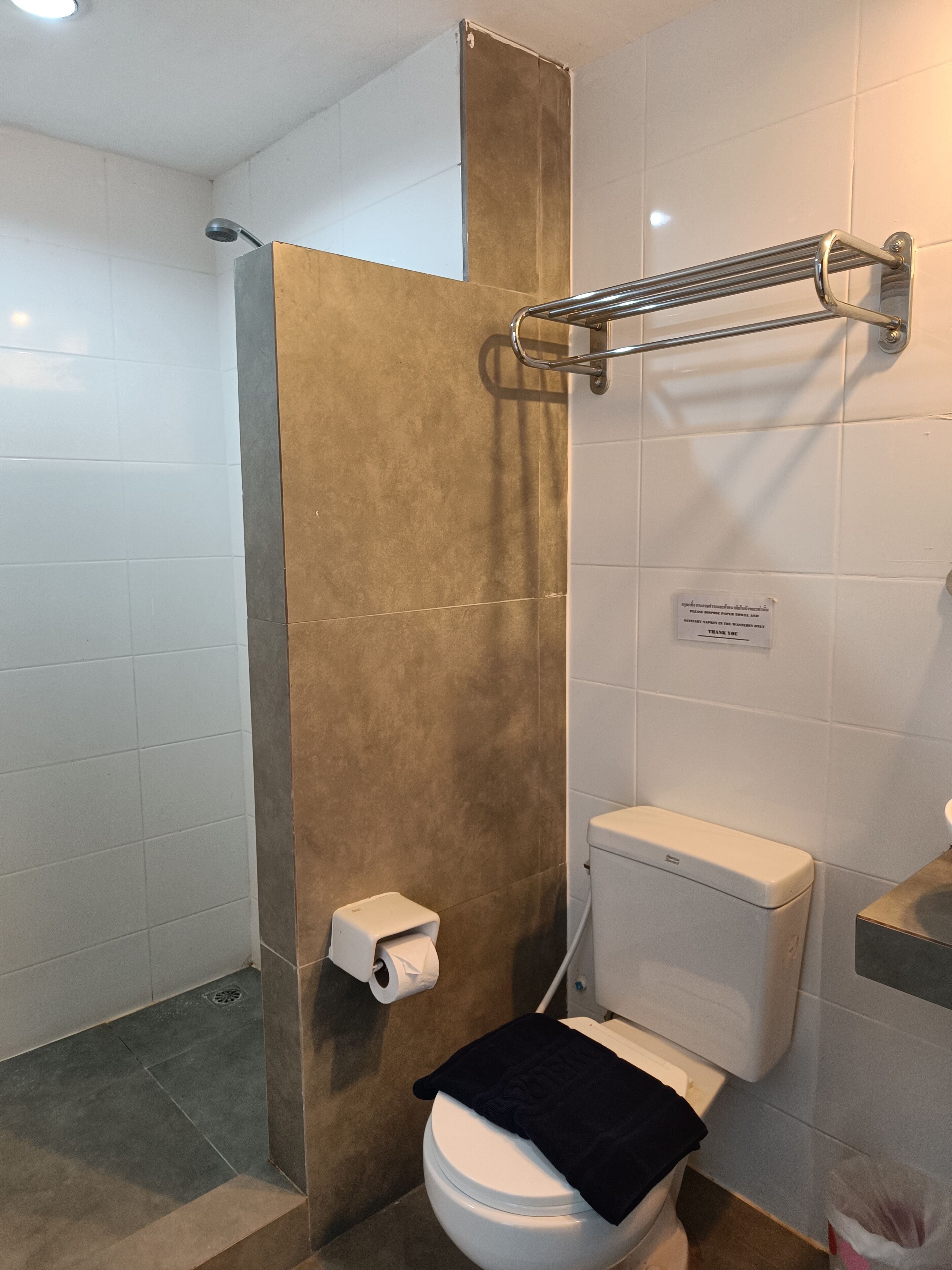 Un baño con inodoro, ducha y barra para toallas.
