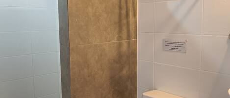 Un baño con inodoro, ducha y barra para toallas.