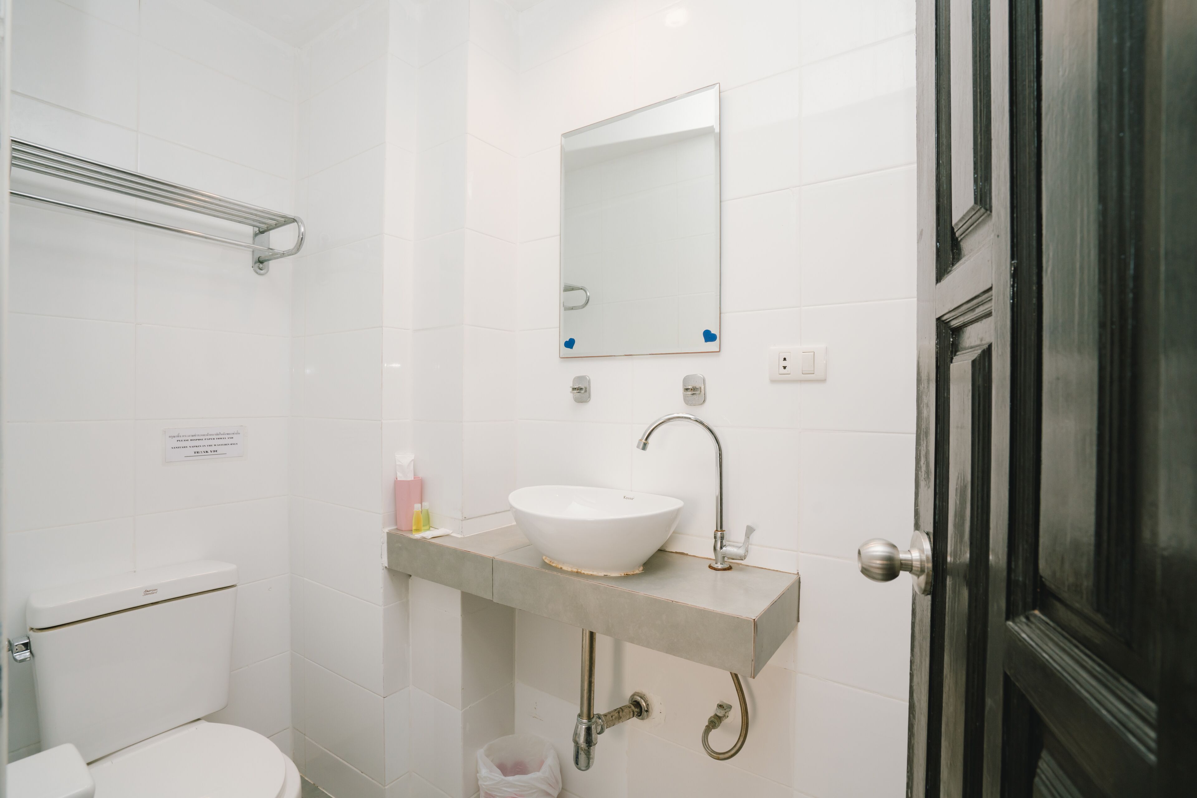 A bathroom with a white toilet, a sink with a mirror above it, and a door to the right.