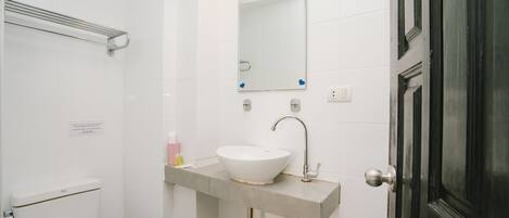 A bathroom with a white toilet, a sink with a mirror above it, and a door to the right.