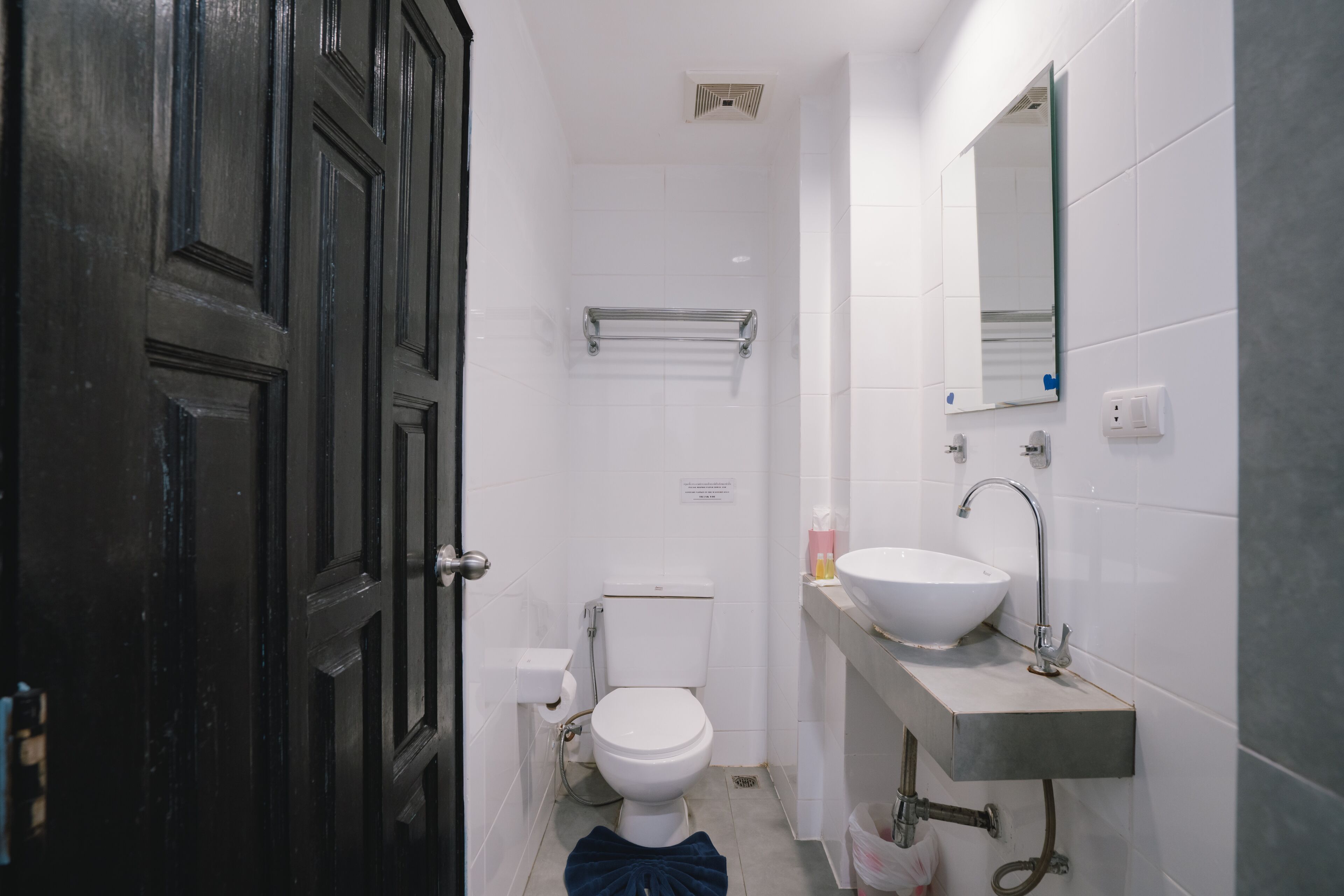 A compact bathroom with a white toilet, a sink, and a mirror.