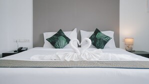 A neatly made bed with a white duvet and a decorative swan towel arrangement.