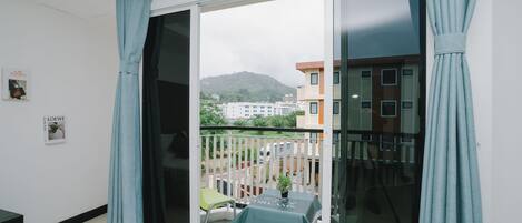 Een balkon met een tafel, stoelen en uitzicht op gebouwen en heuvels.