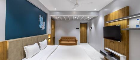 A modern hotel room with a large bed, a flat-screen TV, a ceiling fan, and a wooden accent wall.