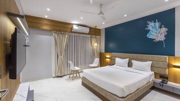 A modern hotel room with a large bed, a flat-screen TV, a desk, and a ceiling fan.
