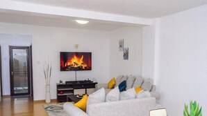 A modern living room with a grey sofa, a flat-screen TV, and a fireplace. - George's Fully Furnished 2 Bedroom Apartment (Nairobi)