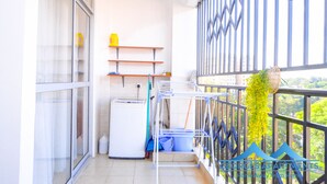 A balcony with a washing machine, drying rack, and shelves. - George's Fully Furnished 2 Bedroom Apartment (Nairobi)