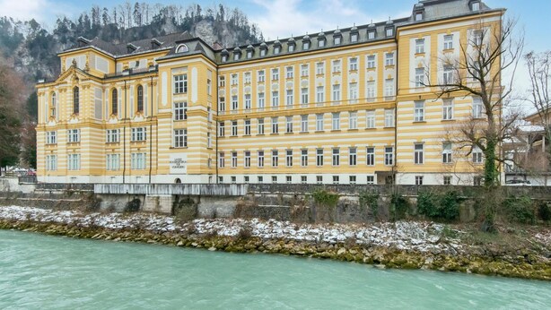 A large, yellow building with multiple windows and a stone wall in front. - Holiday Home Feldkirch Panoramic Views (Feldkirch)