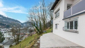 A modern building with a balcony and a view of a town and hills in the background. - Holiday Home Feldkirch Panoramic Views (Feldkirch)