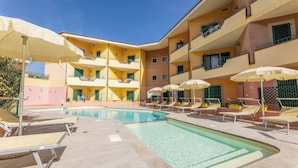 A pool area with sun loungers and umbrellas, surrounded by multi-story buildings with balconies. - Residence I Mirti Bianchi (Santa Teresa di Gallura)