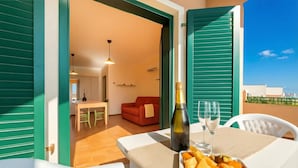 A balcony with a table set for two, a bottle of champagne, and a plate of fruit. - Residence I Mirti Bianchi (Santa Teresa di Gallura)