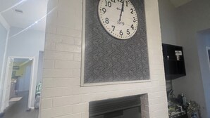 Ein Wohnzimmer mit einer großen Wanduhr, einem Kamin und einem an der Wand befestigten Fernseher.
