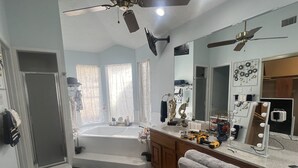 Ein Badezimmer mit Badewanne, Waschtisch und einem großen Spiegel mit Beleuchtung.