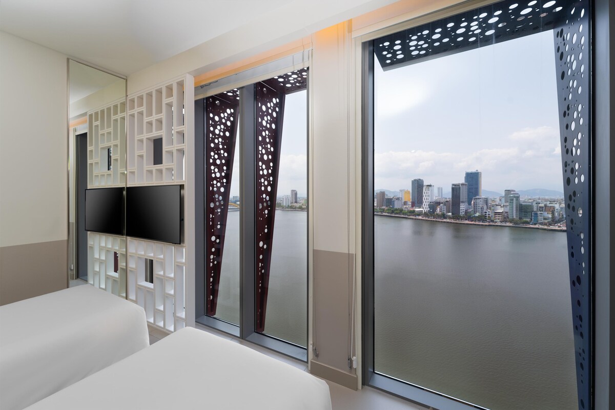 A hotel room with a city view, a TV, and a sliding door with a cityscape view.