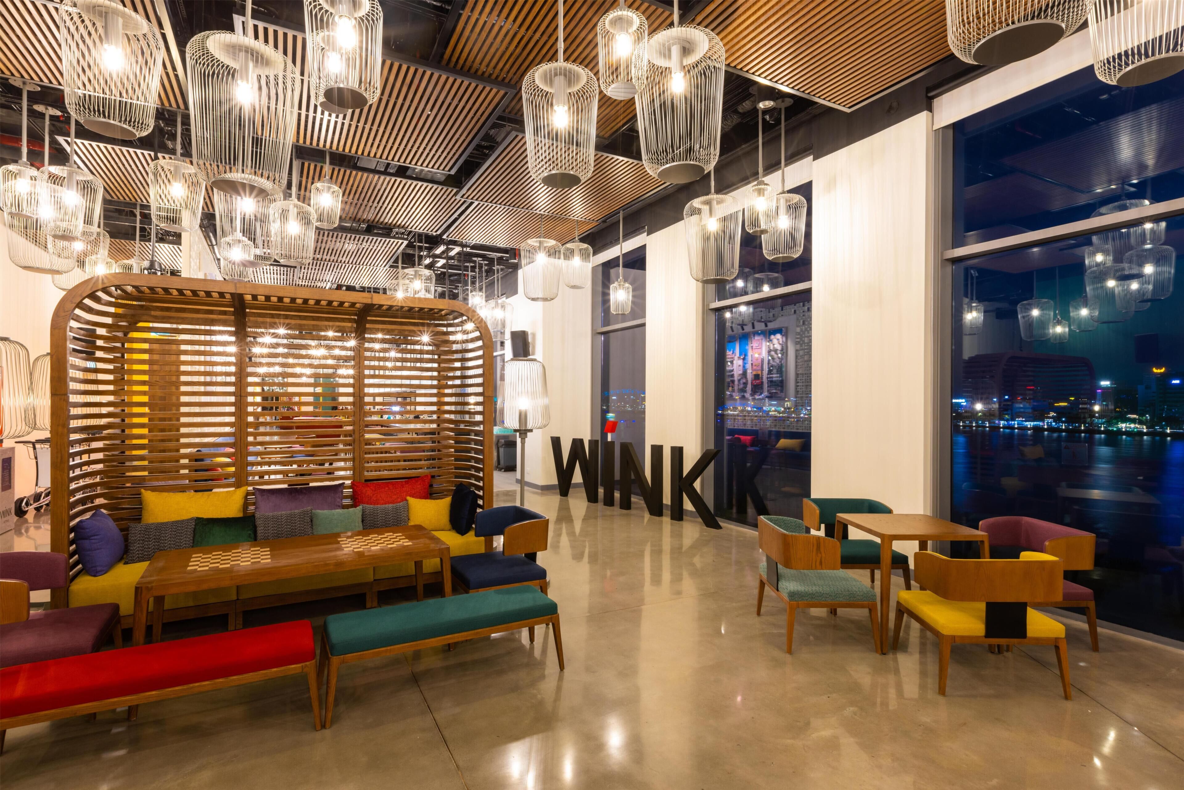 A modern interior with wooden furniture, hanging lights, and a large window with a city view.