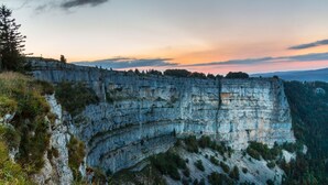 Une grande falaise au sommet incurvé, entourée d’arbres et de végétation.
