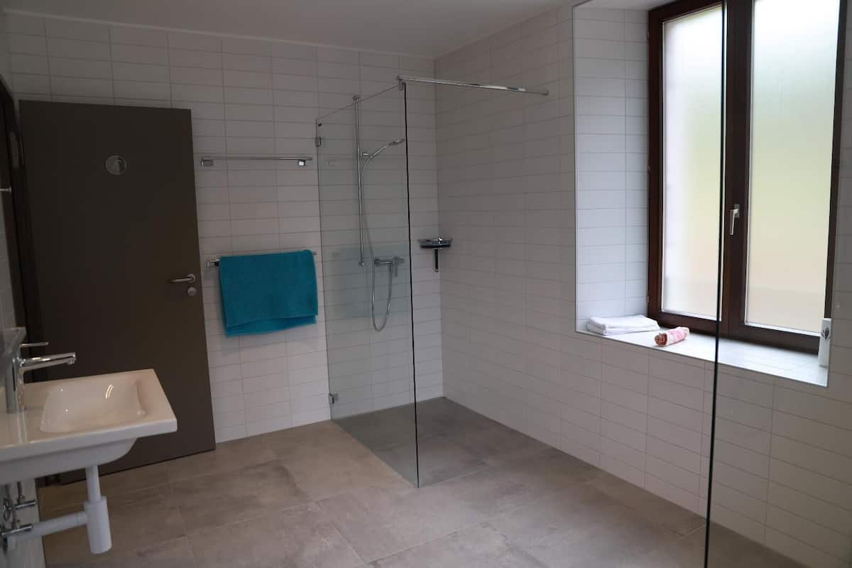 Een moderne badkamer met een douchecabine van glas, een wastafel en een raam met uitzicht.