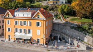 Un hôtel doté d’une terrasse avec restaurant, de panneaux solaires sur le toit et d’un mur de pierre en arrière-plan.